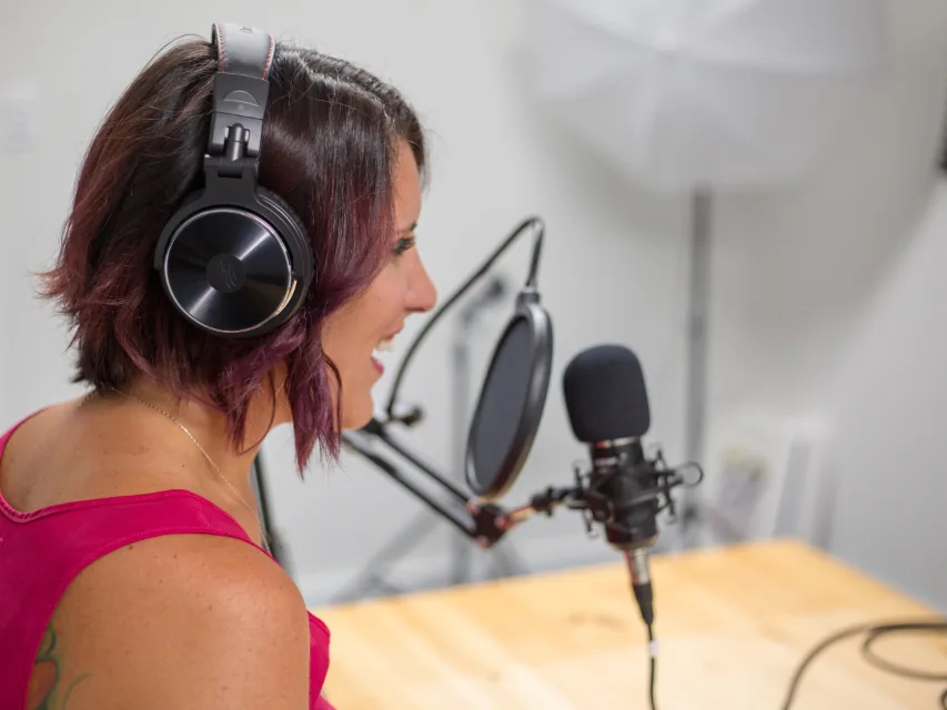 A podcaster recording into a studio microphone wearing headphones.