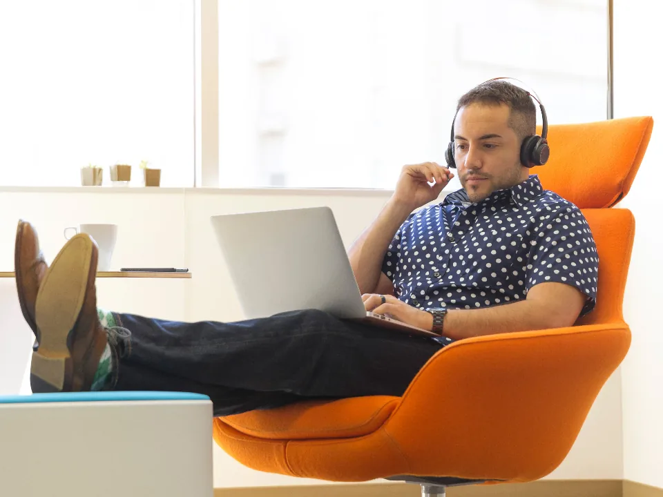 A video editor in headphones working on a laptop.