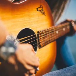 Close-up of hands playing an acoustic guitar.